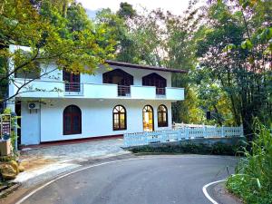 a white house with a road in front of it at Diyakalana Rest in Ginigathena