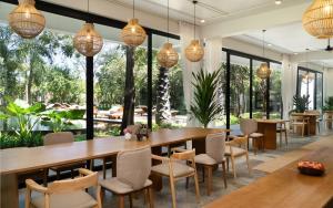 una sala da pranzo con tavoli e sedie e grandi finestre di The Elephant a Siem Reap