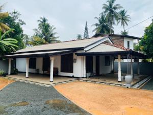a small white house with a driveway at Open Sky Villa in Hikkaduwa