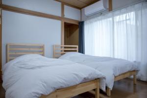 a bedroom with a bed with white sheets and a window at 伊豆の宿 静川 in Ito