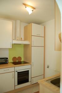eine Küche mit weißen Schränken, einem Herd und einem Kühlschrank in der Unterkunft Ferienwohnung Leeb in Sirnitz