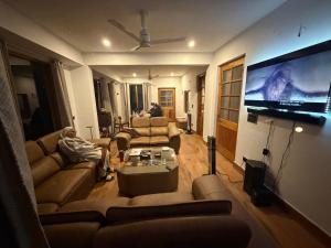a living room with couches and a flat screen tv at Lifessenza Homestay in Khajjiar 