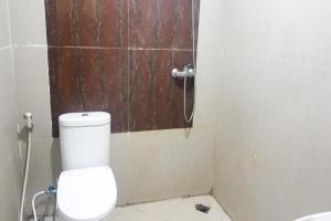a bathroom with a toilet and a wooden door at Hotel O Aida Lestari in Sebulu +8 photos