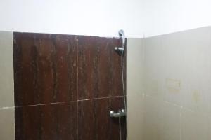 a shower with a wooden door in a bathroom at Hotel O Aida Lestari in Sebulu