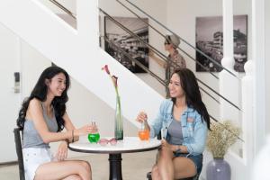 two women sitting at a table with drinks at Cacha Bed in Bangkok