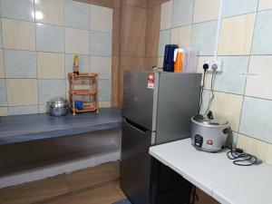 a small kitchen with a refrigerator and a counter at Dongorit Cabin 2 The three rooms in Kampong Kundassan