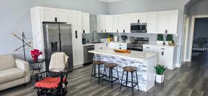 a kitchen with white cabinets and a kitchen island with bar stools at The Blue House in Hitchcock +16 photos