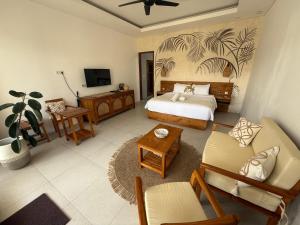 a bedroom with a bed and a couch and a tv at Santai Suites Nusa Dua in Nusa Dua