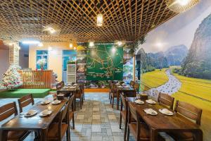 een restaurant met houten tafels en stoelen en een muurschildering bij Tam Coc Sweet Shelter Bungalow in Ninh Binh