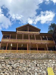 a large wooden building with a stone wall at Mountain Nest Stay in Jibhi