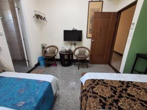 a room with two beds and a table and two chairs at Kinmen Dongshan B&B in Jinning