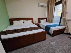 a bedroom with two beds and a window at Kinmen Dongshan B&B in Jinning