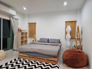 a bedroom with a large bed and a ottoman at Tee Phak CNX Room D in Chiang Mai +8 photos