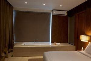 a bathroom with a tub and a bed in a room at Sukavi in Paravūr +6 photos
