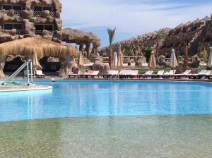 einen Pool in einem Resort mit Stühlen und Sonnenschirmen in der Unterkunft Caves Beach Resort Adults Only in Hurghada