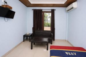 a living room with a chair and a television at Mekarsari Hotel By ARBA in Tjipitjung Tiga