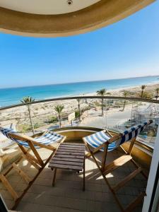 duas cadeiras e uma mesa numa varanda com praia em Espadon Apartment em Mahdia