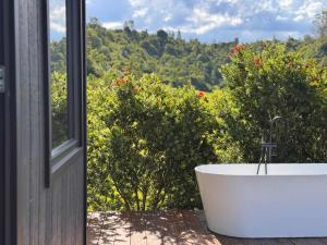 a bath tub sitting next to a window with trees at Tiny Georgie in Picton