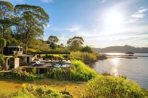 a house on a river with a boat in the water at Inap Retreat Boutique Cabin Kintamani in Kubupenlokan