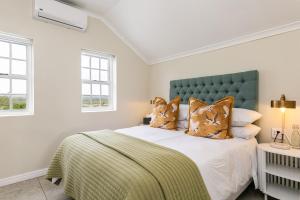 a bedroom with a bed with a green headboard and pillows at Abalone Hotel & Villas 2 Bedroom Apartment in Paternoster +15 photos