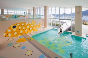 a pool in a building with a person in the water at RISONARE Shimonoseki in Shimonoseki