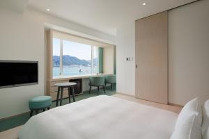 a hotel room with a large bed and a large window at RISONARE Shimonoseki in Shimonoseki