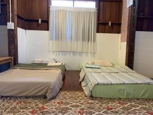 two beds sitting in a room with a window at Ka Prao Kai Hostel in Pai