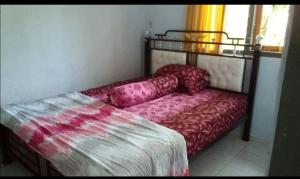a bed sitting in a room with a red bedspread at Ruteng YosPrima Garden in Lao