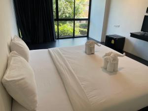 two stuffed elephants sitting on top of a white bed at Azz Hotel in Chiang Mai