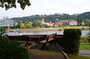 een picknicktafel en banken naast een rivier bij Ferienwohnung an der Elbe in Dresden