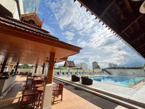 una piscina in un hotel con sedie e un padiglione di The Empress Hotel a Chiang Mai