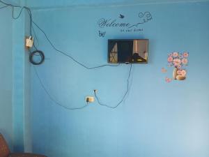 a room with a blue wall with a sign that reads welcome to our home at iya lee guest hauz in Capissayan +1 photo