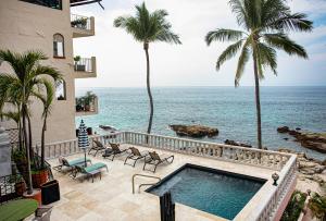 a resort with a swimming pool and palm trees and the ocean at Quinta Maria Cortez Beach Hotel in Puerto Vallarta