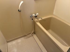 a bath tub with a hose next to a sink at アルピエf 103号室 無料WiFiあります生活しやすい場所です in Kumamoto