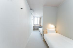 two beds in a room with white walls at atic Guesthouse in Takamatsu