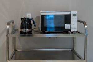 a microwave oven sitting on a metal shelf at atic Guesthouse in Takamatsu