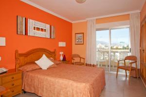 a bedroom with orange walls and a bed and a balcony at Hotel Noguera El Albir in Albir