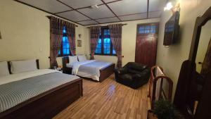 a bedroom with two beds and a chair and windows at Paradise Cottage in Nuwara Eliya