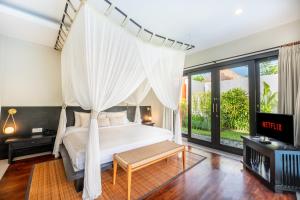 a bedroom with a canopy bed and a tv at Villa Jerami & Spa in Seminyak +23 photos