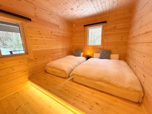 two beds in a room with wooden walls at Second House LUONTO in Tsumagoi