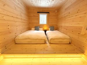 two beds in a room in a wooden cabin at Second House LUONTO in Tsumagoi +10 photos