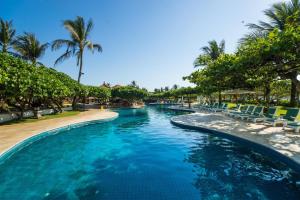 a pool at a resort with chairs and palm trees at Grand Hyatt Bali in Nusa Dua