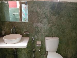 a bathroom with a sink and a toilet and a mirror at Manilal in Battaramulla
