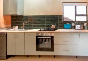 a kitchen with white cabinets and a stove top oven at Fourfields Hogsback in Hogsback +23 photos