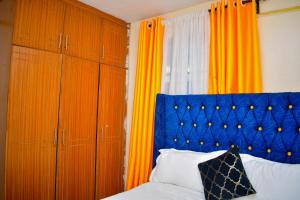 a bedroom with a blue headboard and orange curtains at Cozy Homes in Thika