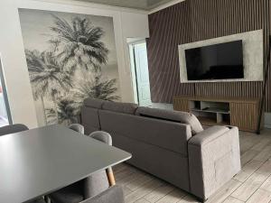 a living room with a couch and a table and a tv at Le repaire de la mare in Salazie