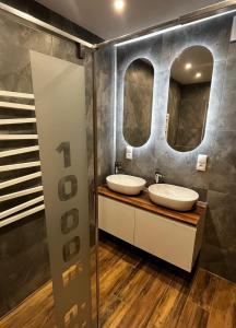 twee wastafels in een badkamer met twee spiegels bij Apartamenty 1000m npm Murzasichle in Murzasichle +19 foto's