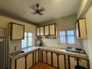 a kitchen with white cabinets and a ceiling fan at The golden villa in Calangute