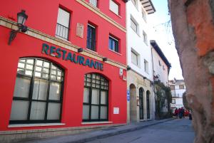un bâtiment rouge avec un panneau de restaurant rouge dans une rue dans l'établissement Hotel Iguareña, à Ezcaray