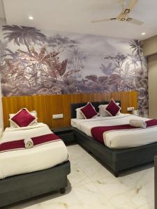 twee bedden in een kamer met een muurschildering. bij Hotel Kiara Eshosans Palace in Shirdi